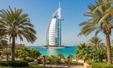 Burj Al Arab Dubai standing tall by turquoise waters and palm trees under clear blue sky