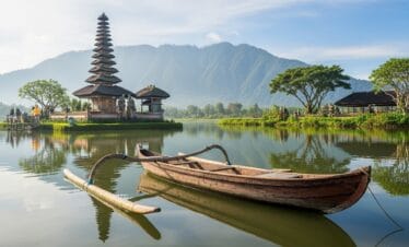 Wide-angle shot of Bali showing canoe on calm water and Balinese pagoda surrounded by greenery