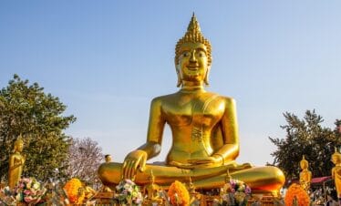 Golden Buddha statue in Pattaya Thailand with sunlight reflecting on intricate details