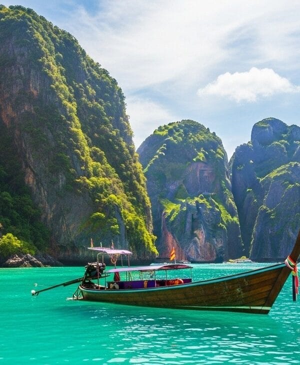 Wide-angle shot of Krabi in Thailand with turquoise water, limestone cliffs, and wooden longtail boat