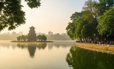 Turtle Tower on Hoan Kiem Lake with morning mist and golden sunlight, highlight of Hanoi travel packages